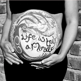 A pregnant belly is decorated with paints stating 'life is truly a miracle' independent midwife